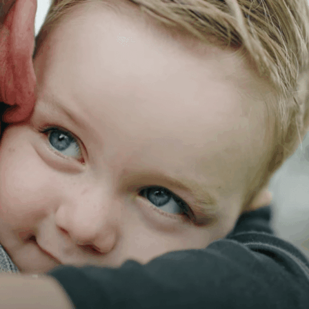 Close Up Of A Happy, Young Little Scholars Student Embracing A Parent Or Trusted Adult Figure