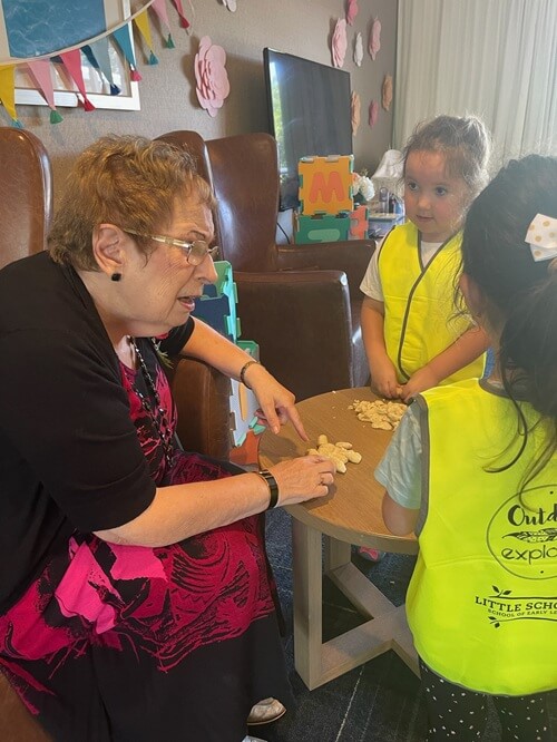 Elderly Mentor Engaging With Young Children In A Small Group Setting, Promoting Collaboration