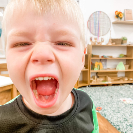 Little Scholars boy yelling with a wide open mouth, depicting strong emotion like anger or intense excitement in the classroom.