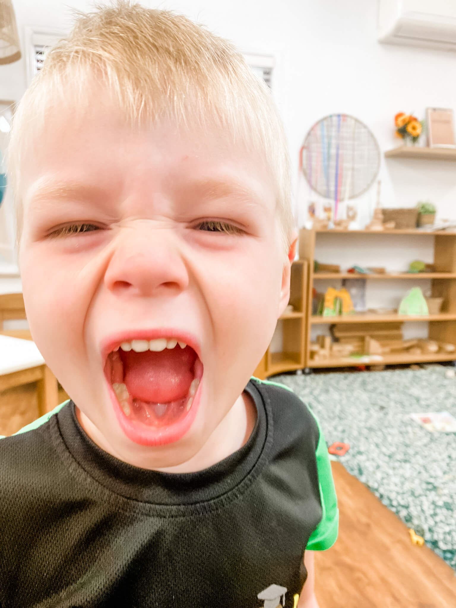 Little Scholars boy yelling with a wide open mouth, depicting strong emotion like anger or intense excitement in the classroom.