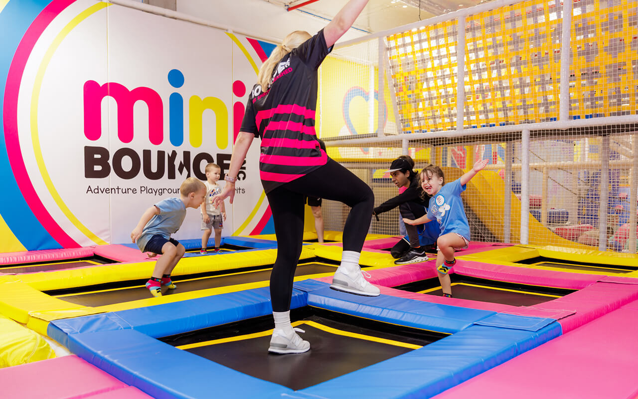 Children and staff playing on colorful trampolines at BOUNCE Mini Bounce Zone indoor playground in Australia.