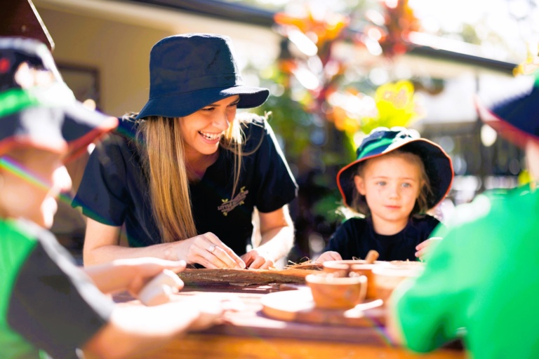 Educator and children engaged in outdoor nature-based learning at Little Scholars Childcare