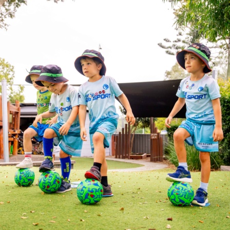 Preschool-aged children practicing soccer skills during sport in early childhood education.